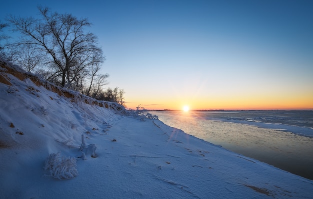 Winter landscape with frozen lake and sunset sky. Composition of nature.