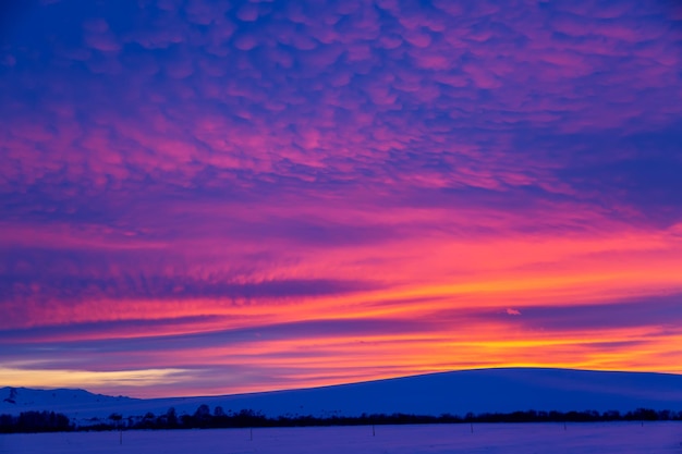 Winter landscape with mountains during amazing vivid saturated beautiful sunset sky in pink, purple and blue colors. Sunset background.