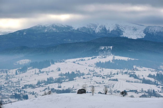 Winter landscape with small village houses between snow covered forest in cold mountains