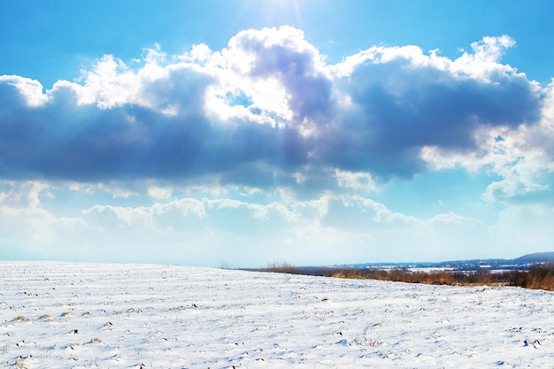 Photo winter landscape with snowy field and picturesque sky with sunlit clouds