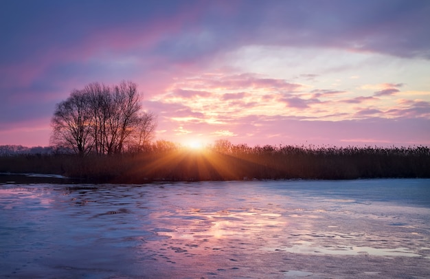 Photo winter landscape with sunrise sun and frozen river.