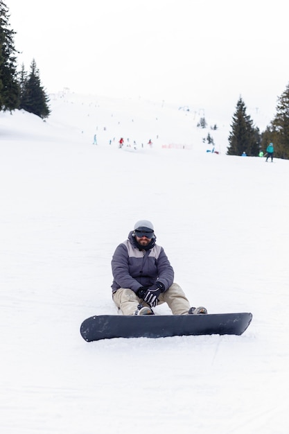 Winter, leisure, sport and people concept - Snowboarder sitting at the top of a mountain and enjoying scenery