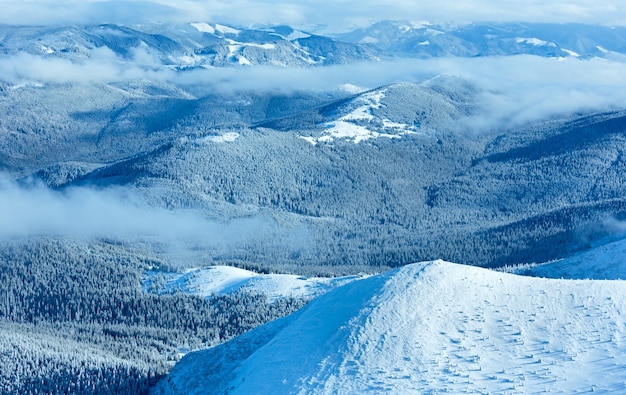 Winter mountain landscape with low-hanging clouds. View from the mount top  (Carpathian, Ukraine).