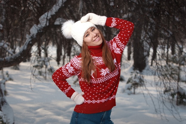 Winter outdoor portrait of cute positive young girl smiling and having fun on natural background in park winter forest