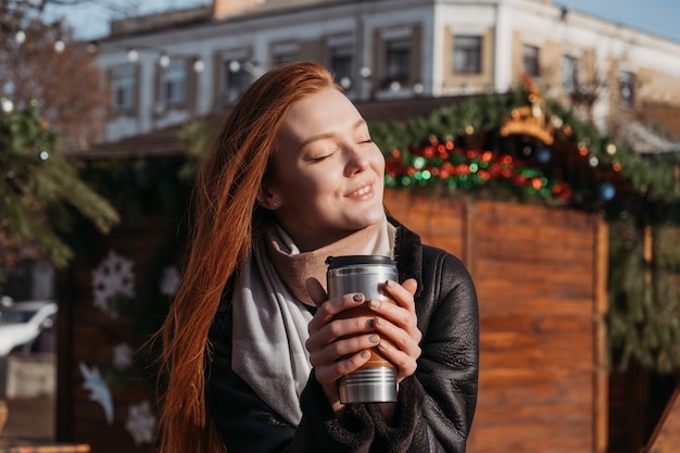 Winter outdoor portrait of a red-haired woman in natural tones. Young woman enjoying life