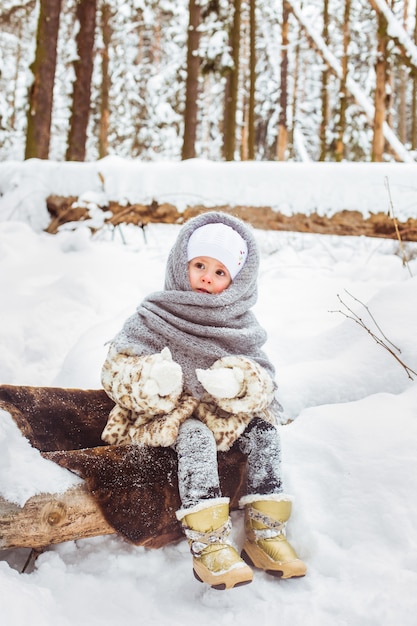 Winter portrait of cute smiling child girl on the walk in sunny snowy forest