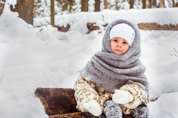 Winter portrait of cute smiling child girl on the walk in sunny snowy forest