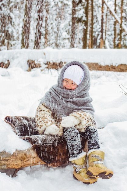 Winter portrait of cute smiling child girl on the walk in sunny snowy forest