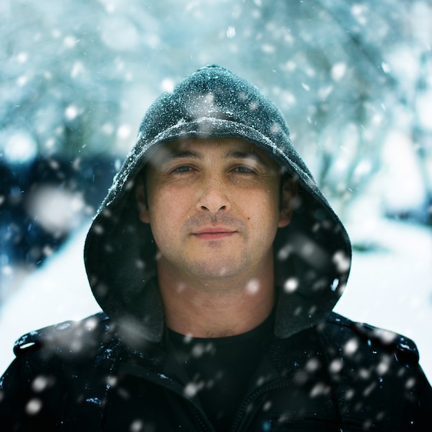 Winter Portrait of a man wearing hood in snow