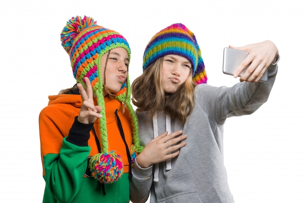 Winter portrait of two happy beautiful teenage girlfriends in knitted hats