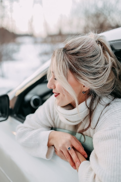 winter road trip concept, happy traveling girl looking out of car window in nature