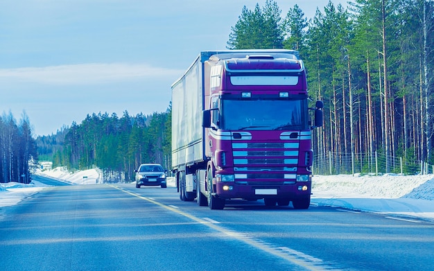 Winter road with snow. Truck in Finland. Lorry car and cold landscape of Lapland. Europe forest. Finnish City highway ride. Roadway and route snowy street trip. Delivery in downhill driveway driving