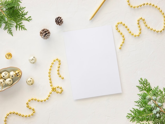 Winter sale mockup. Top view empty A4 sheet with copy space on white background with xmas decorations, fir branches and golden beads. Christmas background with wish list or to do list.