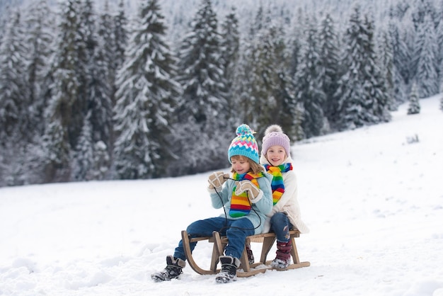 Winter scene with snowy forest little boy and girl sledding in winter kids sibling riding on snow sl