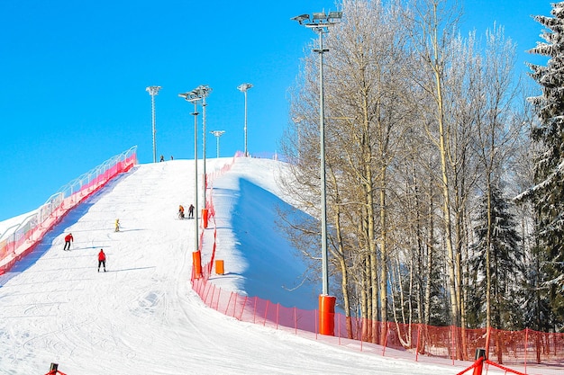 Winter Ski resort Slides skis A ski slope with a red fence and trees in the background