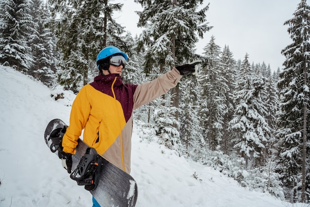 Winter sport and recreation, leisure outdoor activities. Man in ski equipment, wearing safety glasses. Snowboarder man hiking at mountain.