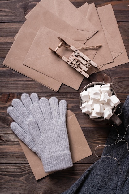 Winter still life Drink with marshmallow wool gloves and craft envelopes on a wooden background