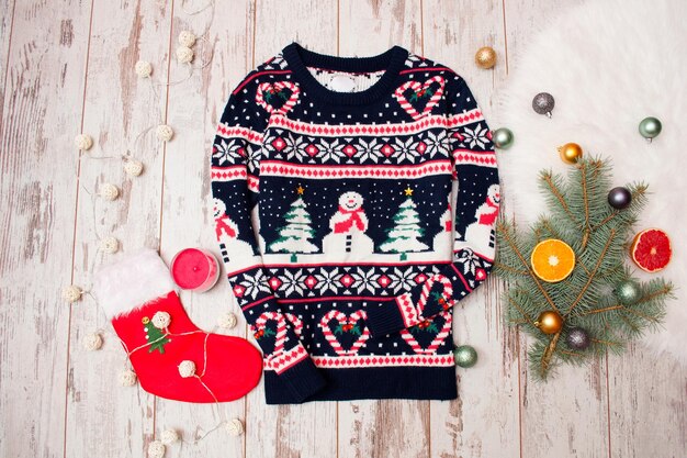 Winter sweater with Christmas pattern on a wooden background fir branch with ornaments and citrus fashion concept