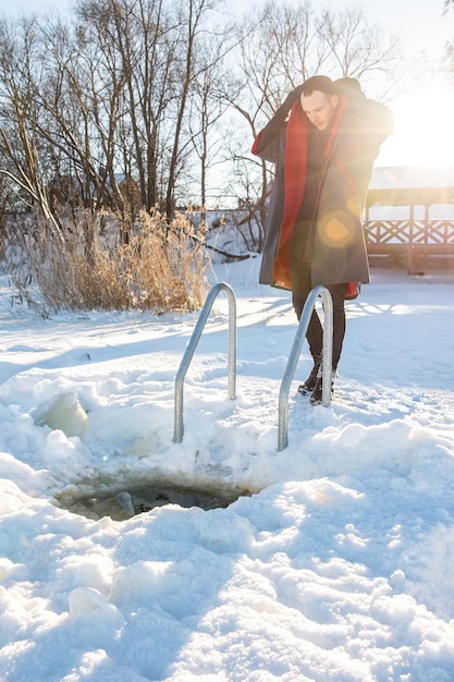 Winter swimmer wrapped in a red towel after a refreshing dip in a snowy ice hole