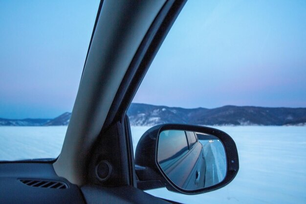 Winter travel The side mirror of the car reflects the winter landscape at sunset