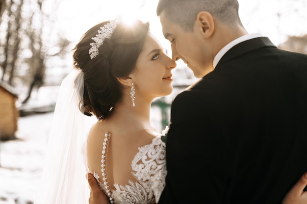 Winter wedding A happy couple in wedding clothes are hugging and smiling in a winter park covered with snow on their wedding day Winter love story of a beautiful couple in snowy winter weather