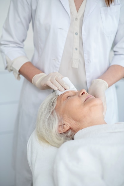 Wiping a face. Cosmetologist wiping the customers face with a napkin