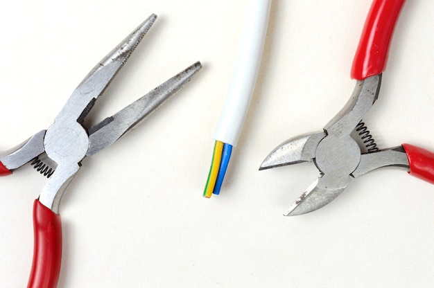 Wire cutters, pliers and wire on a light background. top view