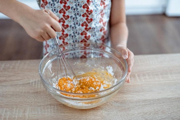 Wire whisk and eggs whipped egg yolks with sugar in a glass bowl