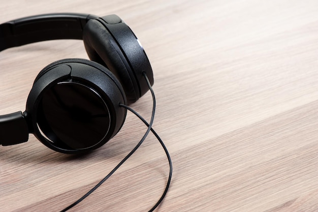 Wired black headphone isolated on wooden background