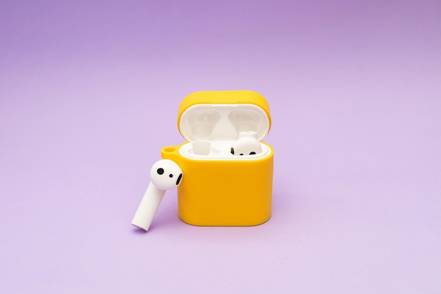 Wireless headphones in a yellow case on a purple background