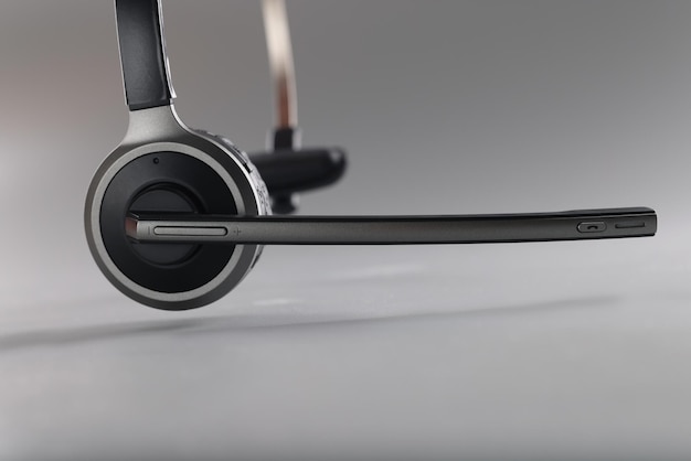 Wireless headset with a microphone on a gray background, close-up. Call center equipment, one ear. Working from home