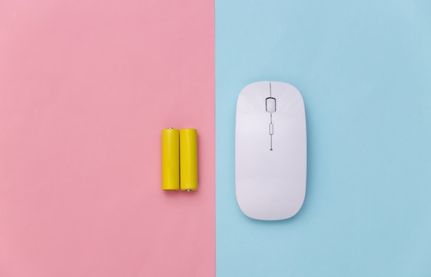 Wireless pc mouse and two batteries on a blue-pink pastel background. Top view