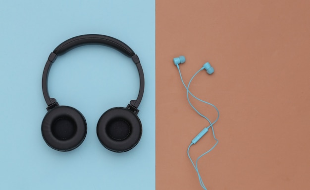 Wireless Stereo headphones and wired earphones on blue brown background. Top view. Flat lay