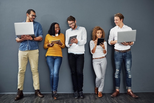 Wireless technology works anywhere Full length shot of a group of businesspeople using tablets and notebooks while waiting in line for a job interview