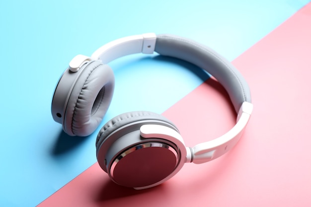 Wireless white and grey headphones on pink-blue space