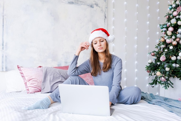 Wish list for Christmas and New Year Young woman controlled by laptop sits