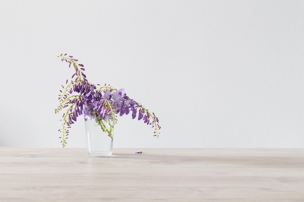 Wisteria flowers in glass vase on wooden table