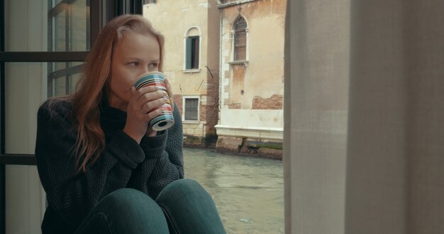 Wistful woman having coffee at home in venice