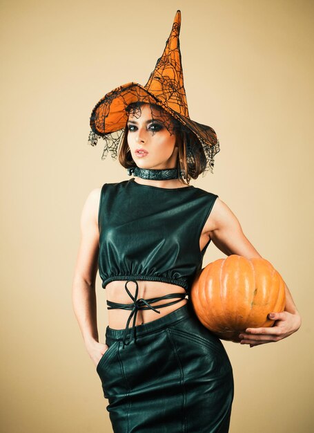 Photo witch in magic hat beautiful young surprised woman in witch hat costume beautiful young surprised woman in witch hat and halloween costume holding pumpkin