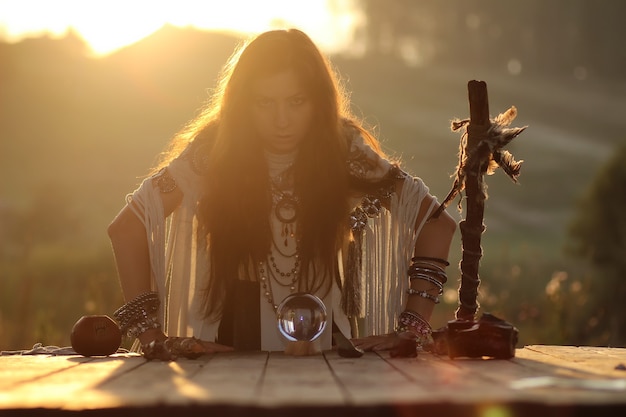 Witch with crystal ball at sunset