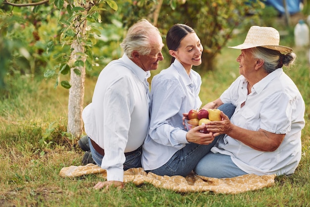 With apples Sitting on the ground Daughter is with her senior mother and father is in the garden