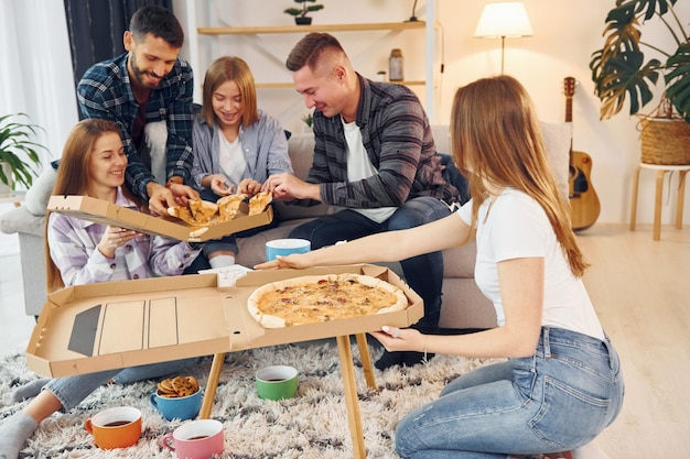 With delicious pizza Group of friends have party indoors together