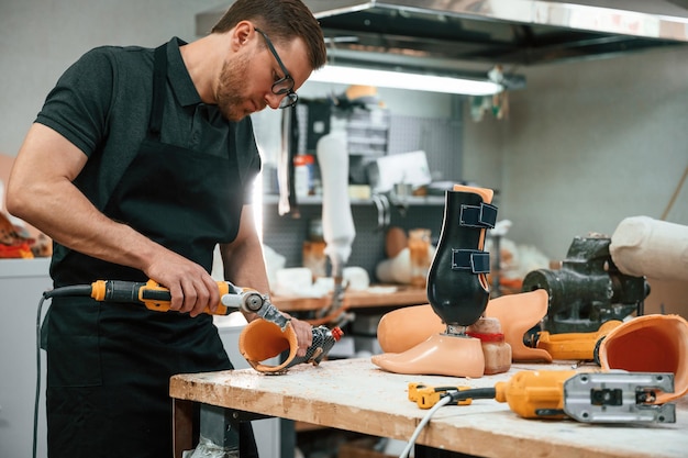 With drill Technician working with prosthesis in modern laboratory