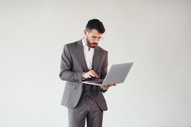 With laptop in hands Young stylish businessman in suit indoors Conception of success