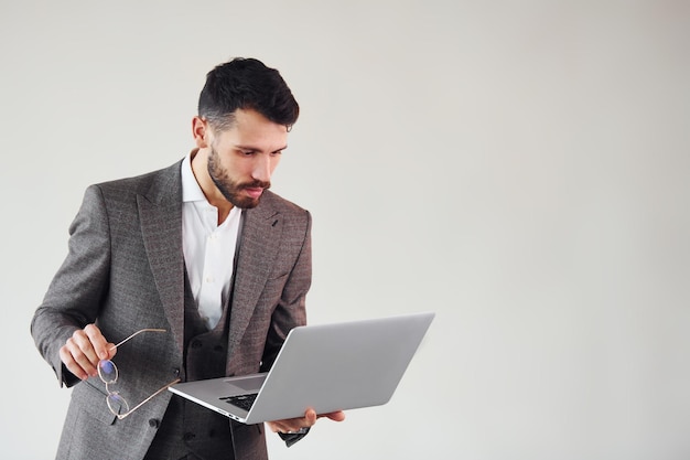 With laptop in hands Young stylish businessman in suit indoors Conception of success