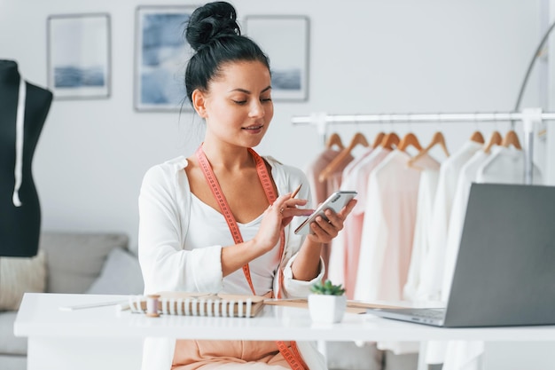 With laptop Seamstress is in her office that is with different clothes