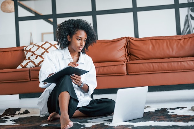 With laptop Young african american woman with curly hair indoors at home