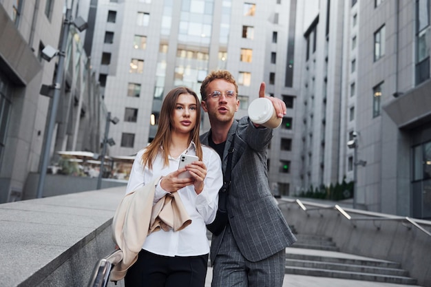 With phone and drink Woman and man in the town at daytime Well dressed people