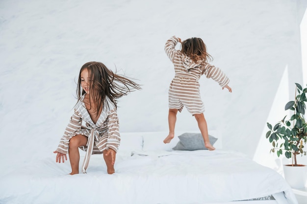 With pillows in hands Two cute little girls indoors at home together Children having fun