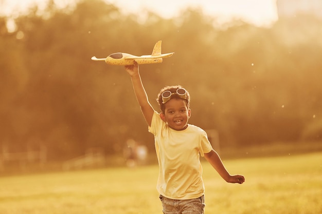 With pilot sunglasses African american kid have fun in the field at summer daytime